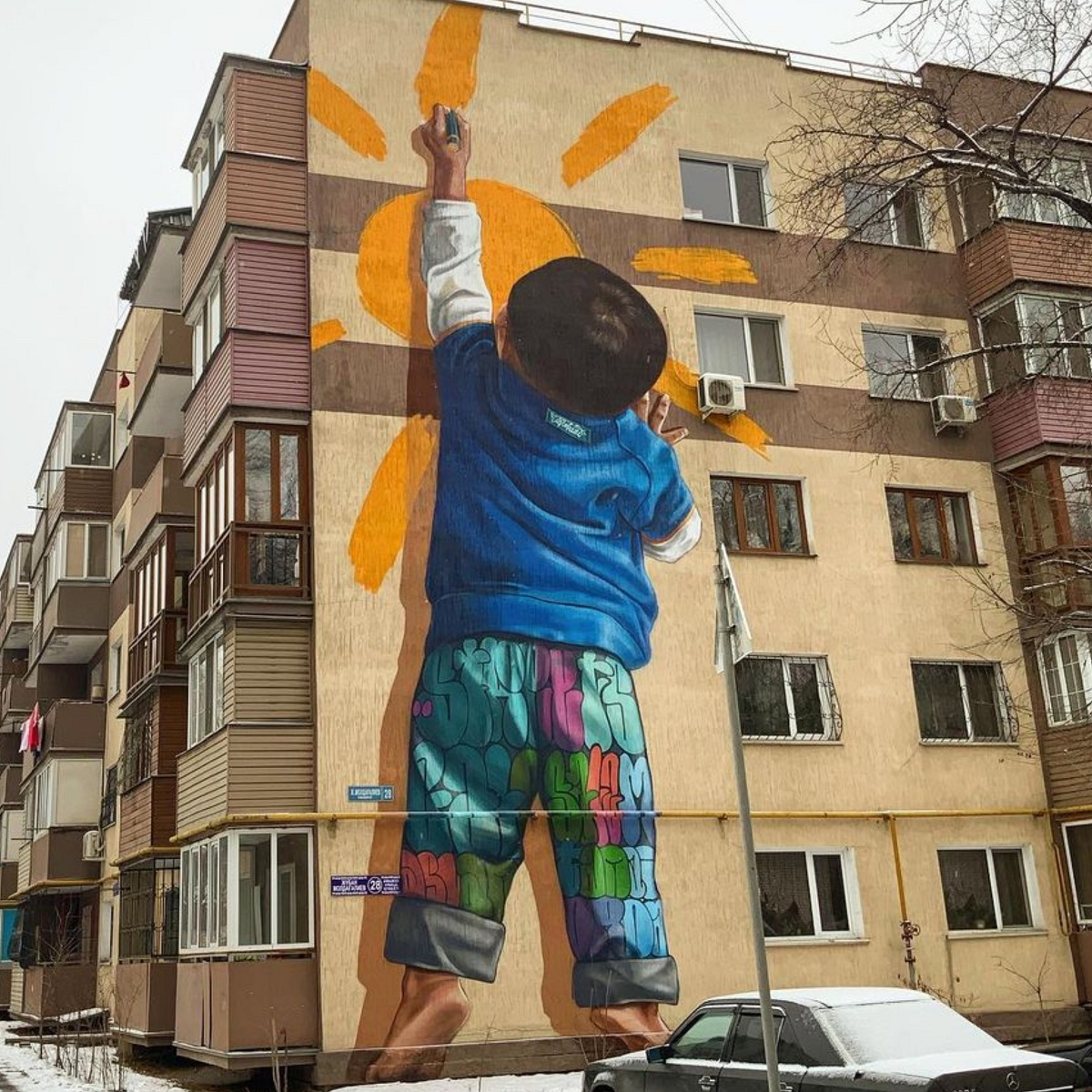 3 pics: Boy painting a sun on a house in Almaty, Kazakhstan